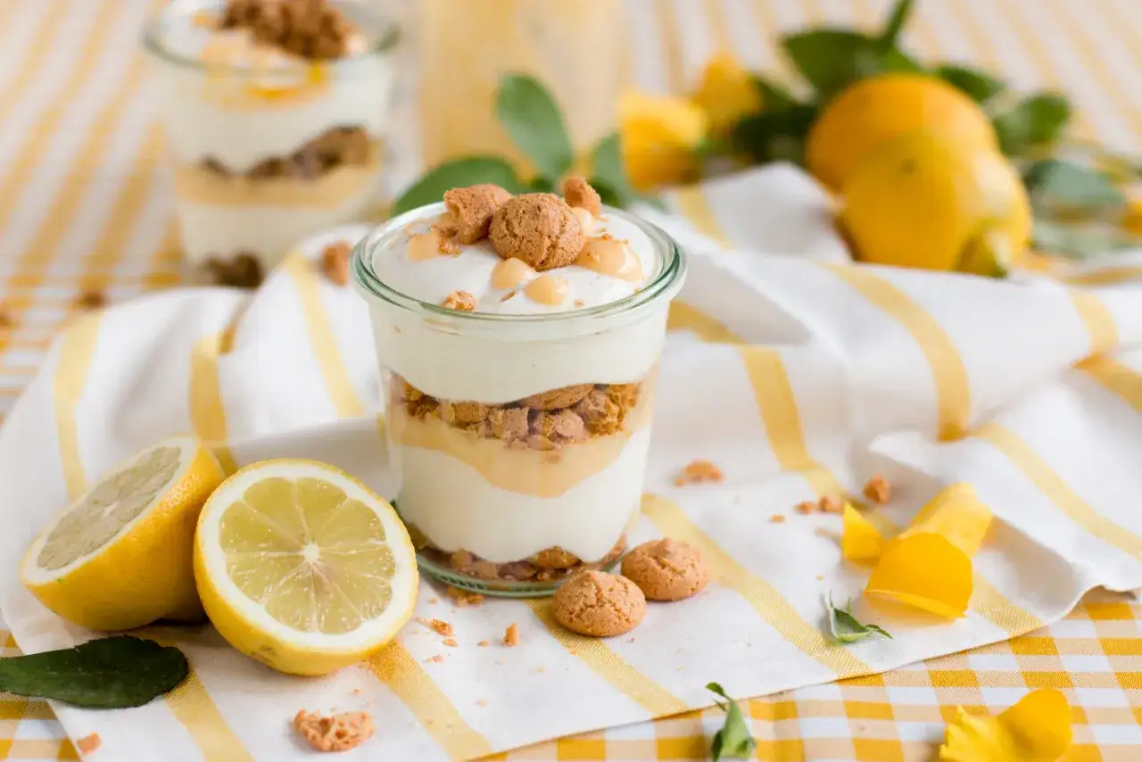Erfrischendes Zitronen Tiramisu im Glas, garniert mit Keksen und Zitronenspalten.