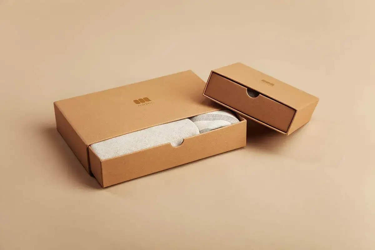 Cajas de cart&oacute;n para empaquetado de productos, una abierta mostrando un textil a rayas, la otra cerrada.