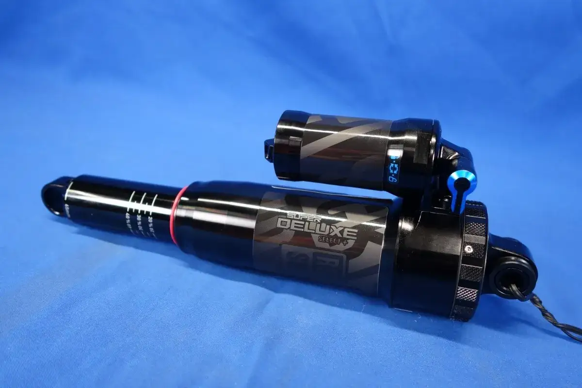 Amortyzator rowerowy RockShox Super Deluxe Select+ z oznaczeniami ugięcia i niebieską dźwignią regulacji.