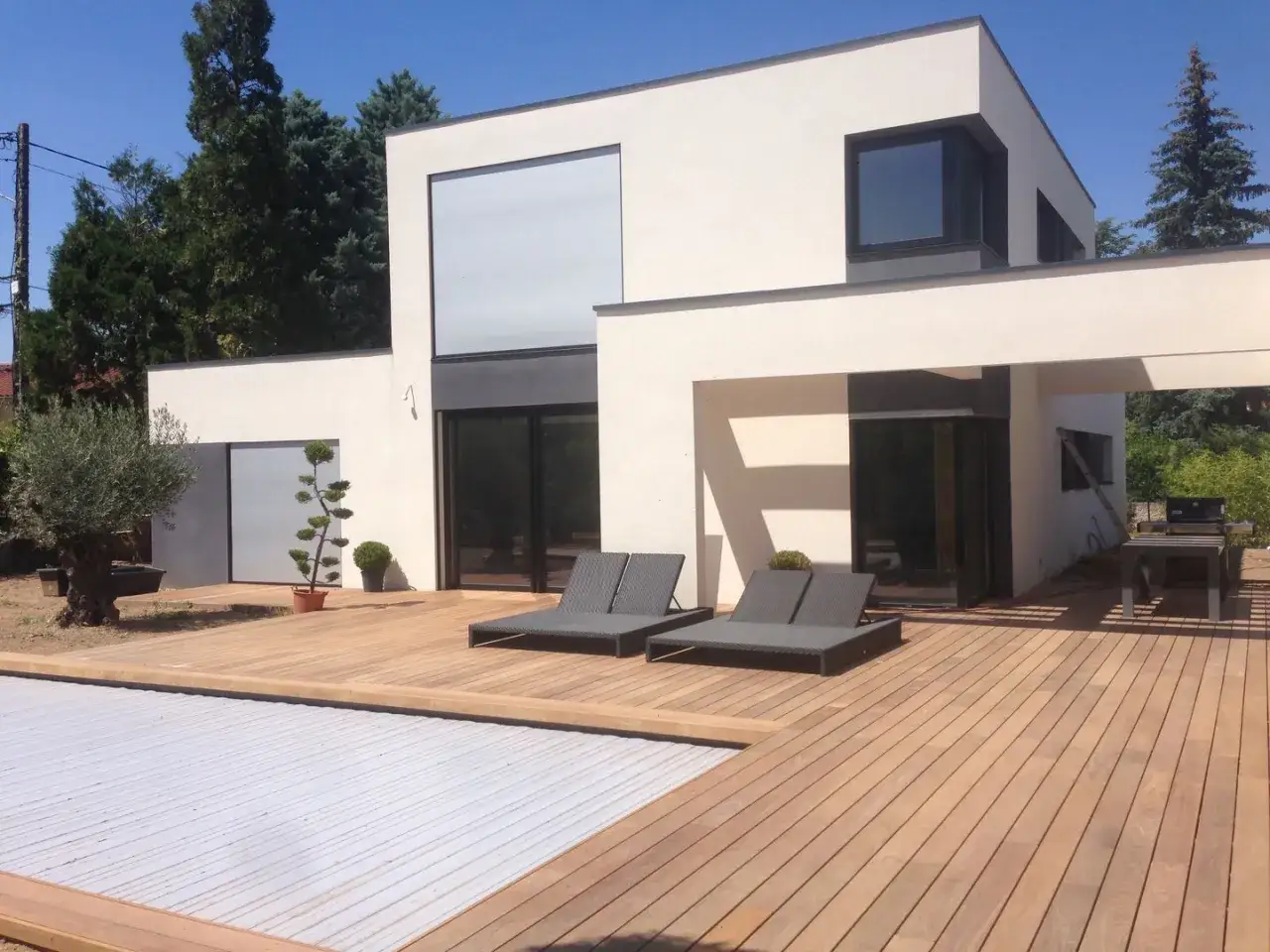 Maison moderne avec terrasse en bois et piscine. Une belle r&eacute;novation ext&eacute;rieure qui invite &agrave; la d&eacute;tente.