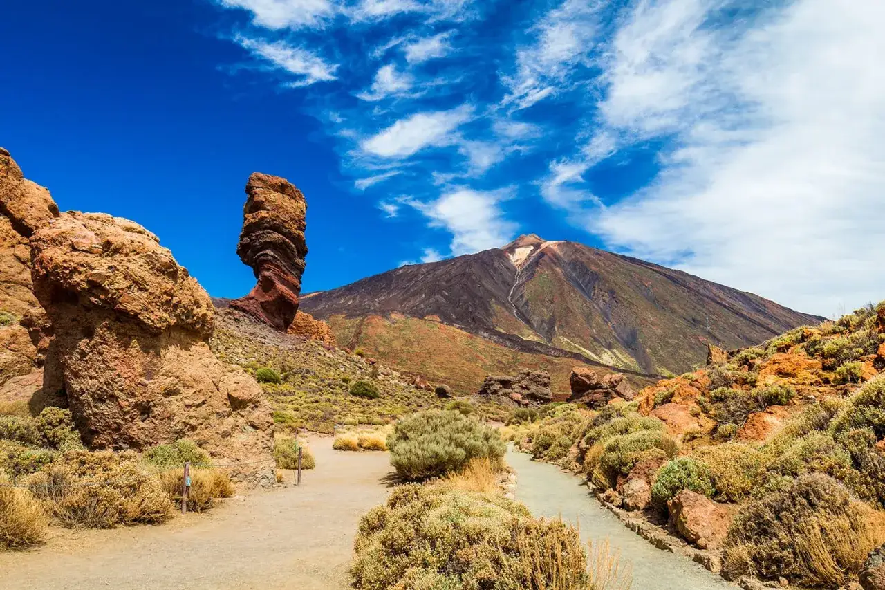 Wulkaniczny krajobraz Parku Narodowego Teide z charakterystyczną skałą Roques de Garc&iacute;a i majestatycznym Teide w tle.