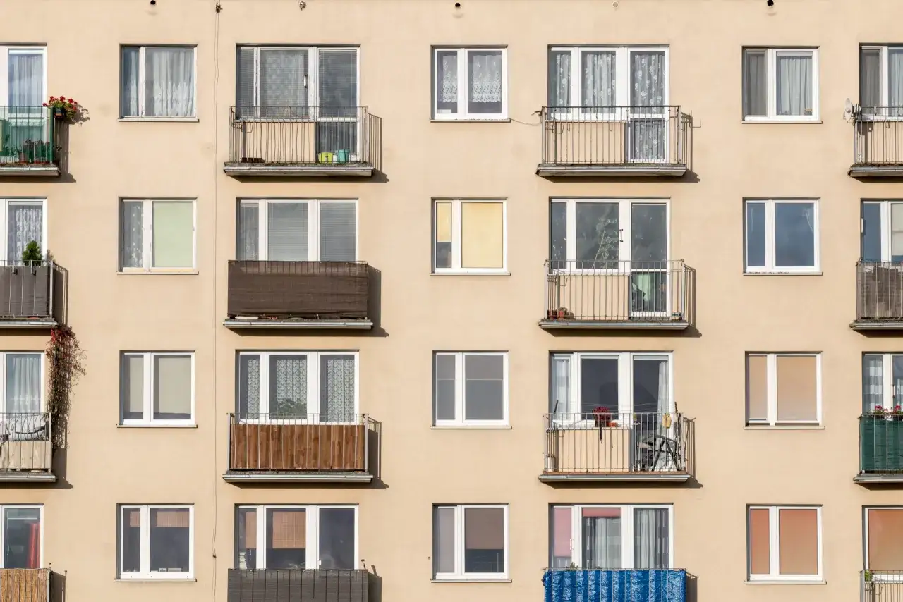 Façade d'immeuble avec de nombreuses fenêtres et balcons. L'aspect hétérogène suggère une rénovation, peut-être une obligation propriétaire changer fenêtres.