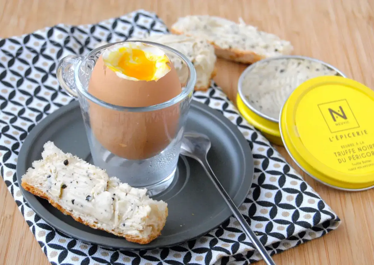 Un &oelig;uf &agrave; la coque parfait, avec son jaune coulant, servi dans un verre. Une tartine beurr&eacute;e &agrave; la truffe noire compl&egrave;te ce d&eacute;lice.