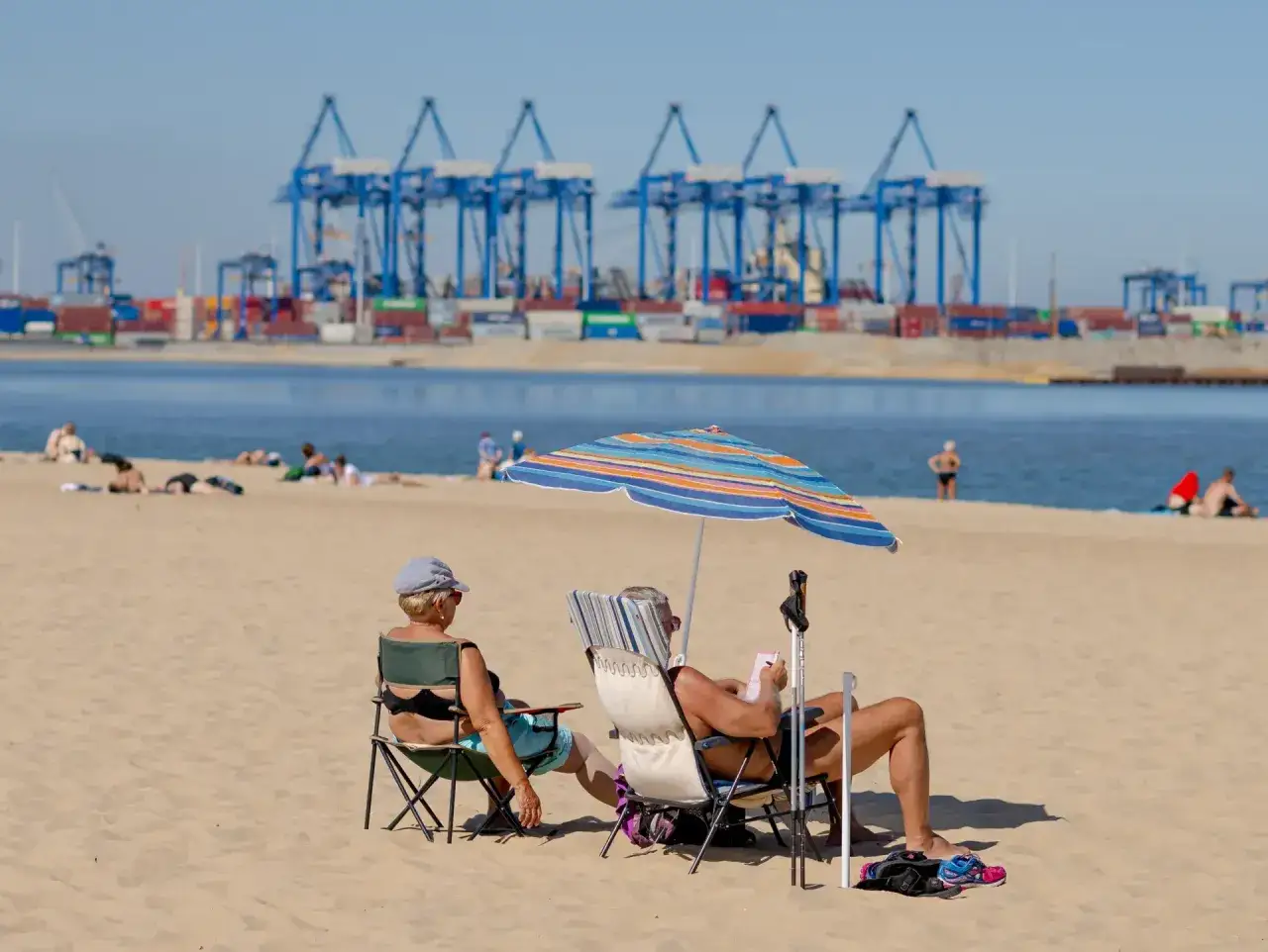 Relaks na plaży w Gdańsku, gdzie przemysłowe dźwigi portowe tworzą nietypowe tło dla wypoczynku. Gdańsk atrakcje dla dorosłych to nie tylko zwiedzanie, ale i takie chwile.