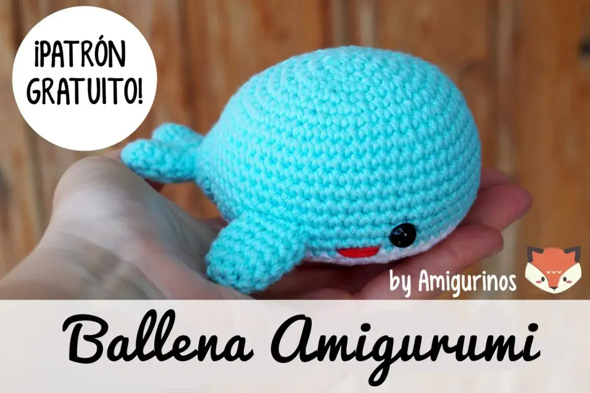 Ballena amigurumi de ganchillo azul, con ojos negros y boca roja, sostenida en una mano. &iexcl;Patr&oacute;n gratuito!
