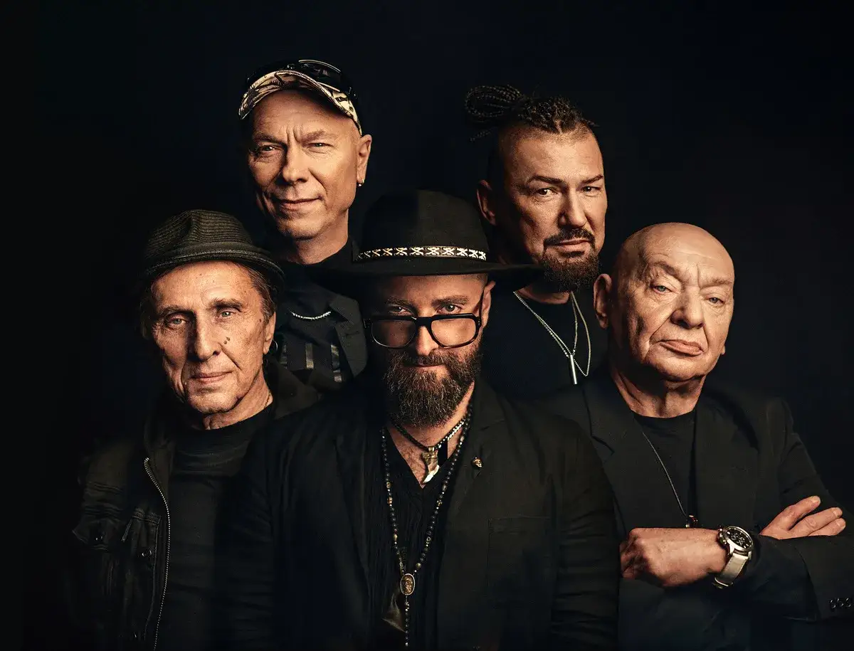 Pięciu mężczyzn w czerni, w tym Łukasz Drapała, prezentuje swoje charakterystyczne style.