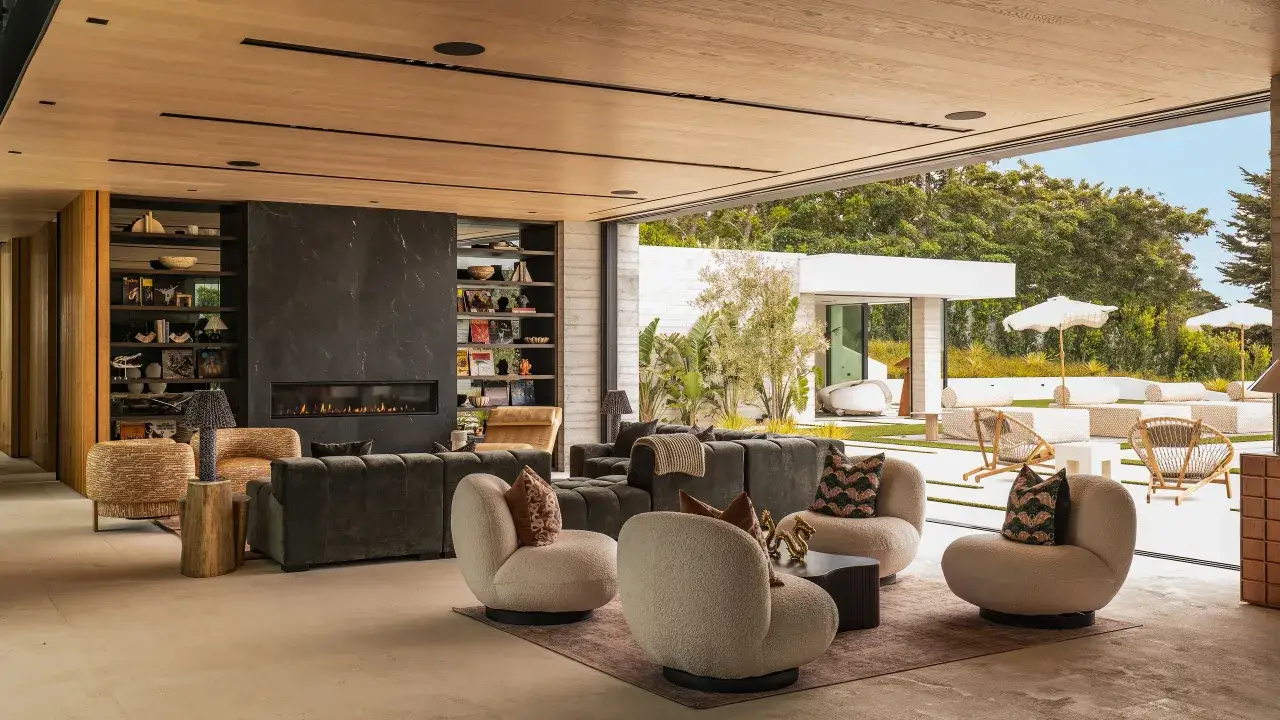 Modern living room with fireplace, plush seating, and open-air patio. This house photography showcases a luxurious, indoor-outdoor living space.