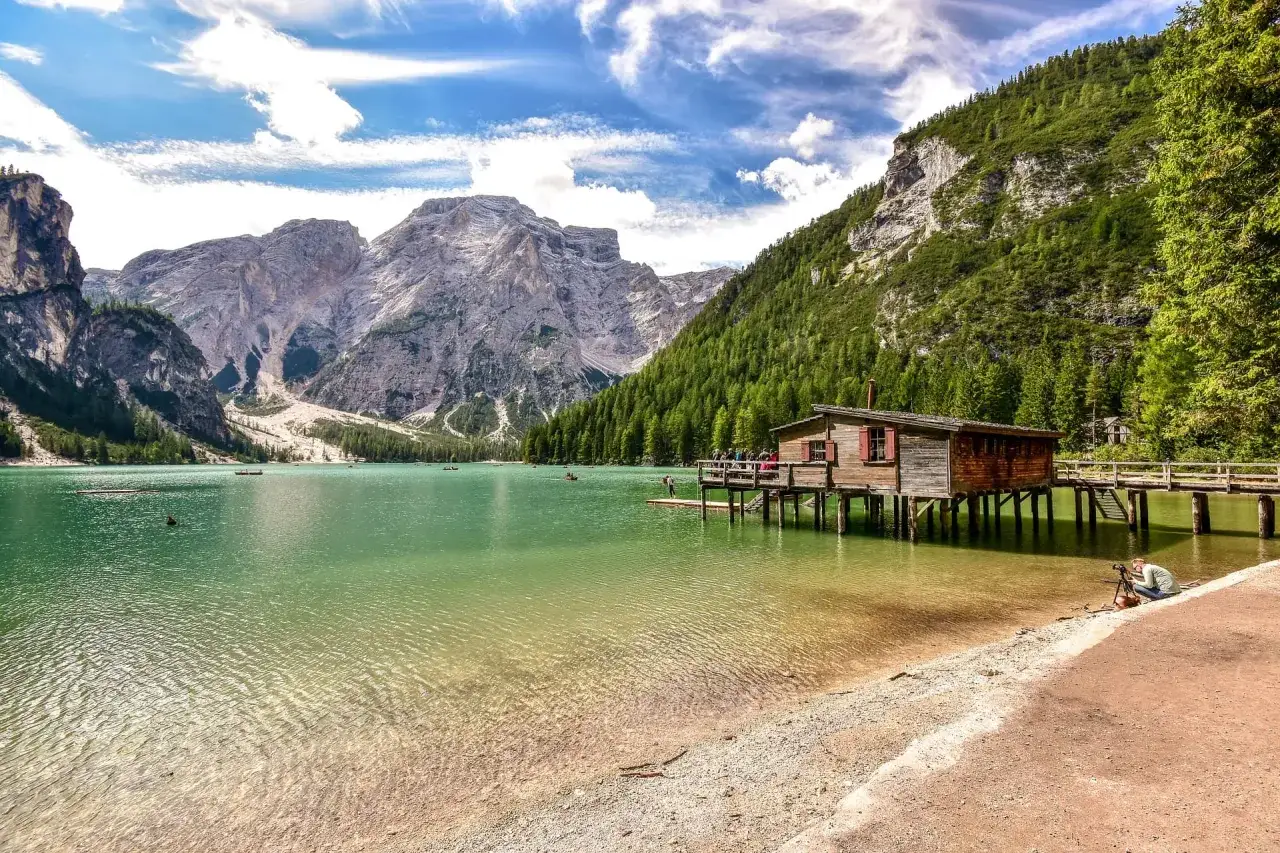 Il **lago di Braies dove si trova** &egrave; incastonato tra maestose montagne, con una baita di legno su palafitte e barche sull'acqua cristallina.