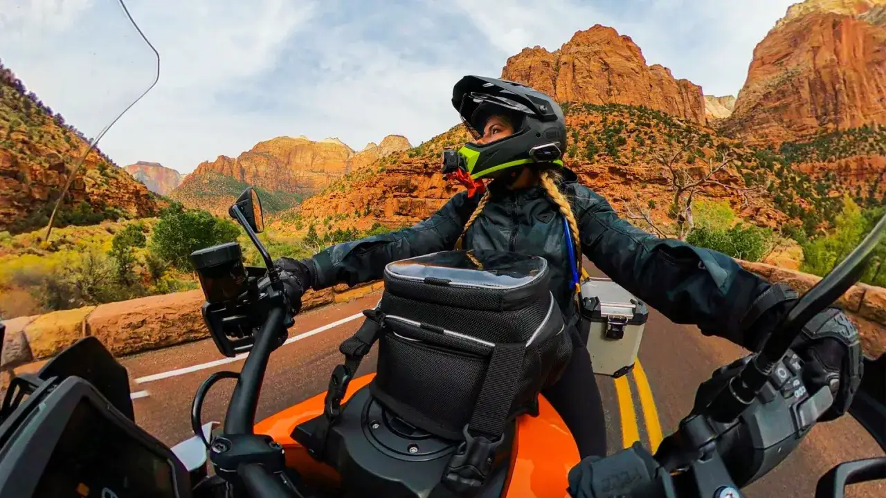 Fahrerin mit GoPro am Helm auf einem Motorrad, die durch eine atemberaubende Berglandschaft fährt.