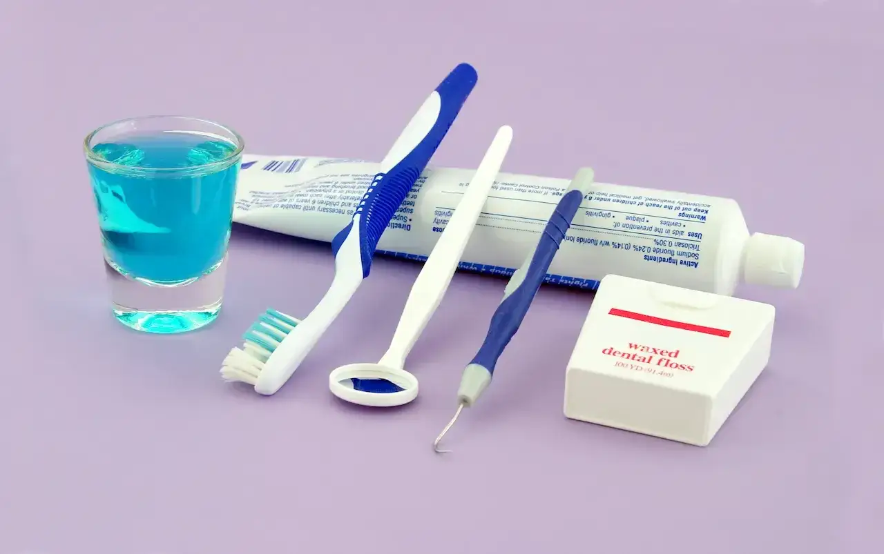 Zestaw do higieny jamy ustnej: płyn, szczoteczka, lusterko, czyścik i nić dentystyczna.