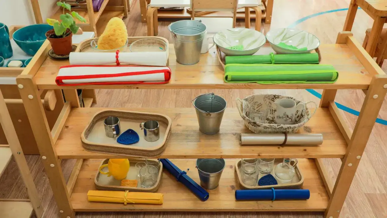 Montessori parents prepare learning stations with practical life activities. This shelf holds materials for pouring, washing, and transferring, fostering independence.