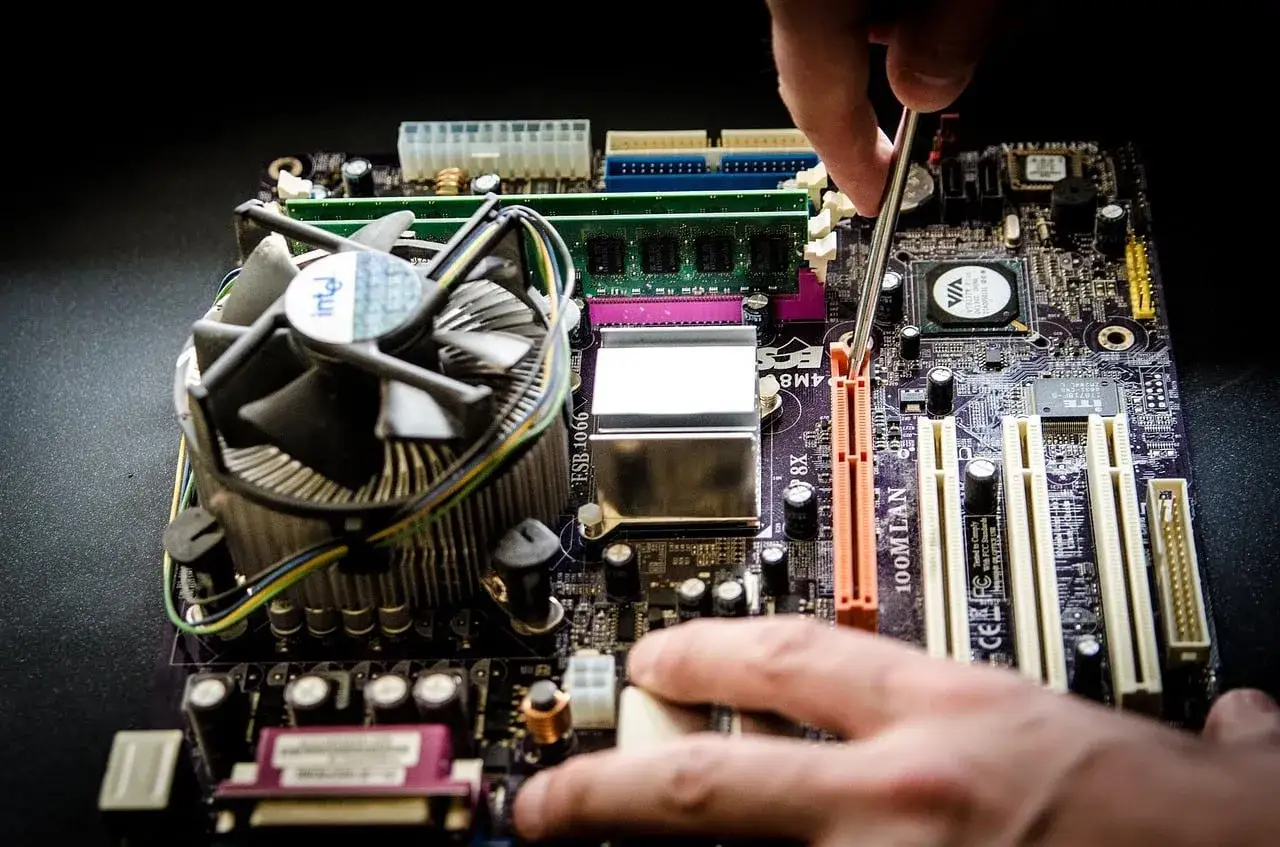 Main d'un technicien effectuant le montage PC, manipulant délicatement les composants d'une carte mère.