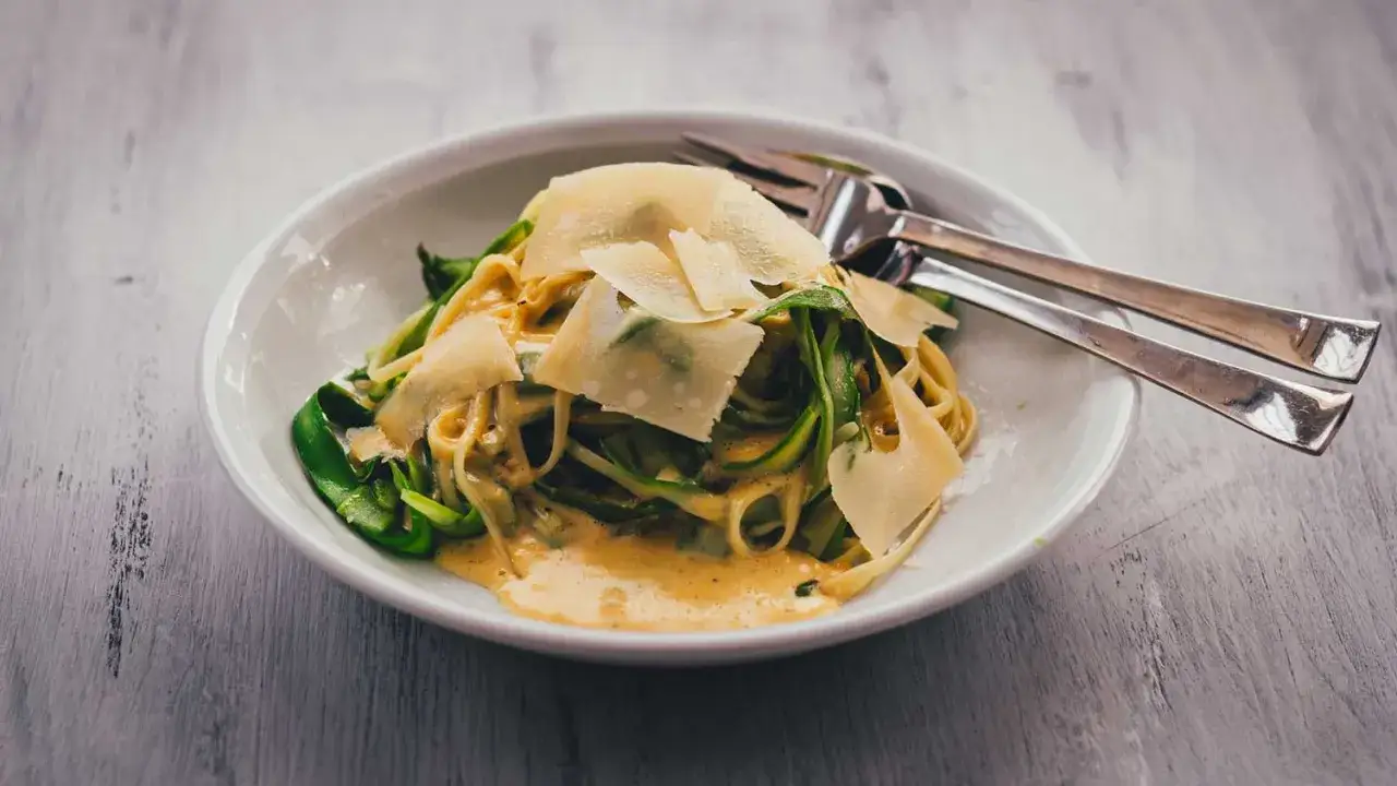 Nudeln mit Spargel und Parmesan in cremiger Sauce, serviert in einer weißen Schüssel mit Gabeln.