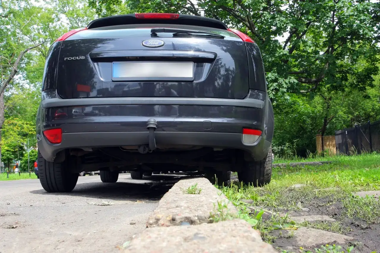 Ciemny Ford Focus zaparkowany przy krawężniku. Widać podwozie, a jego prześwit jest tak niski, że prawie dotyka ziemi.