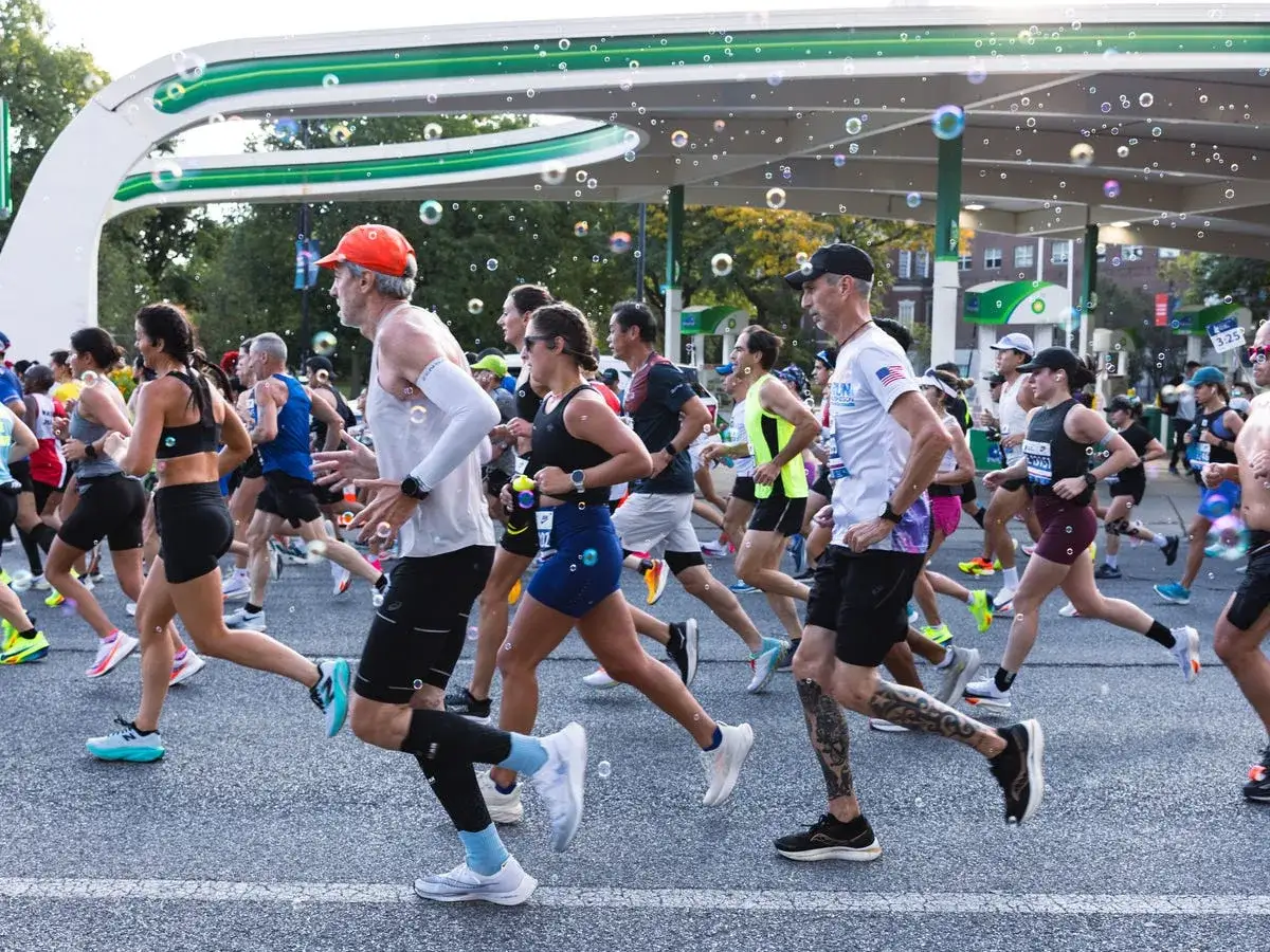 Uczestnicy maratonu biegną, a myślimy o ich plan treningowy maraton. Bańki mydlane unoszą się w powietrzu.
