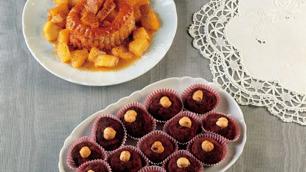 Deliziosi tartufi al cioccolato facili e veloci, guarniti con nocciole, accanto a un dolce di mele speziate.