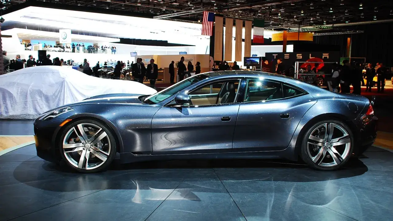 Elegancki, granatowy Fisker Karma błyszczy na wystawie motoryzacyjnej, przyciągając wzrok swoim futurystycznym designem.