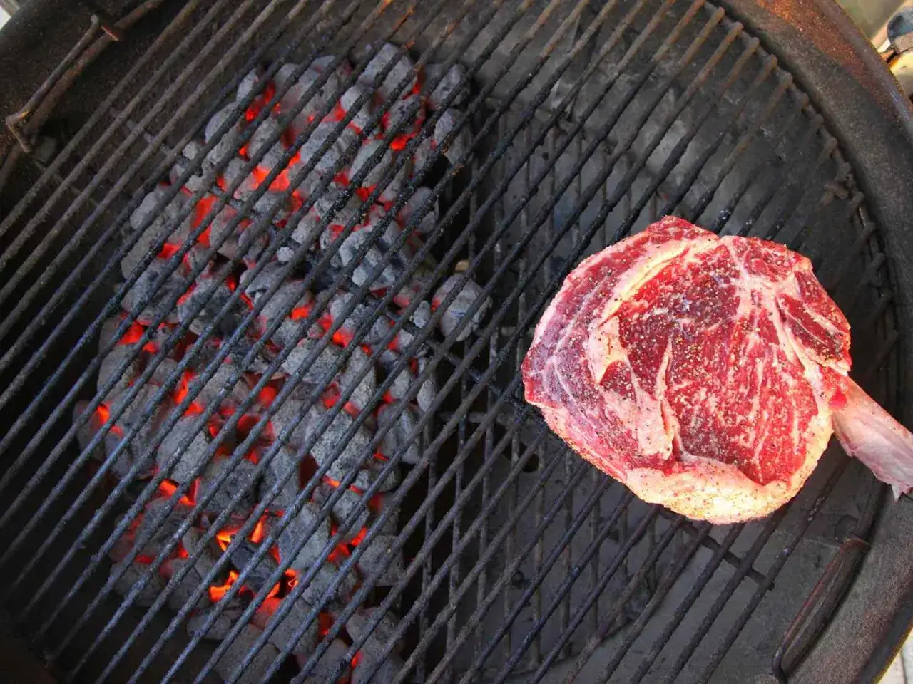 Grillowanie to prawdziwa sztuka! Na ruszcie żarzą się węgielki, a obok leży soczysty stek, gotowy na pyszne grillowanie.