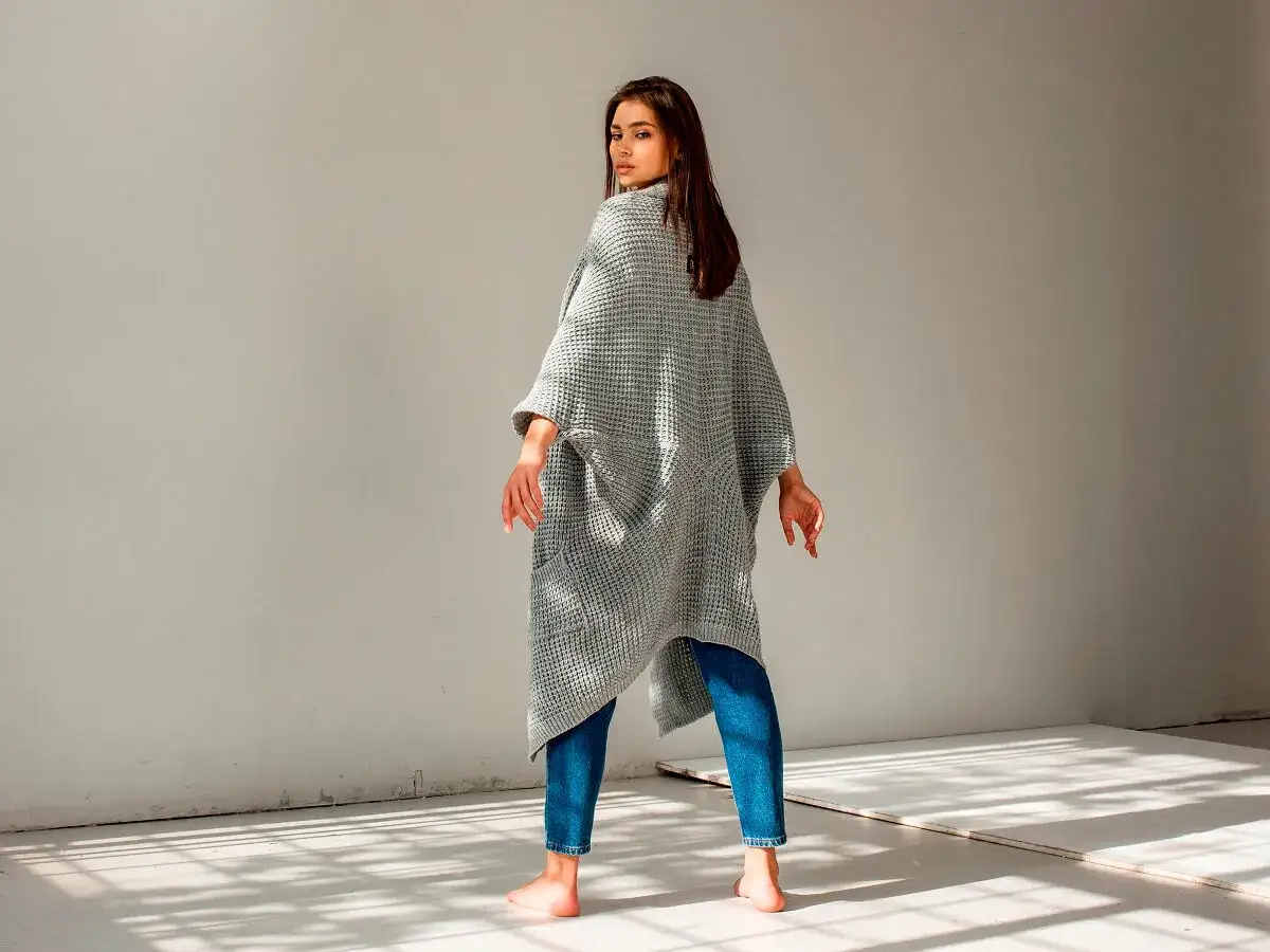 Dziewczyna w szarym swetrze oversize i jeansach. Idealne sweter oversize stylizacje na co dzień.