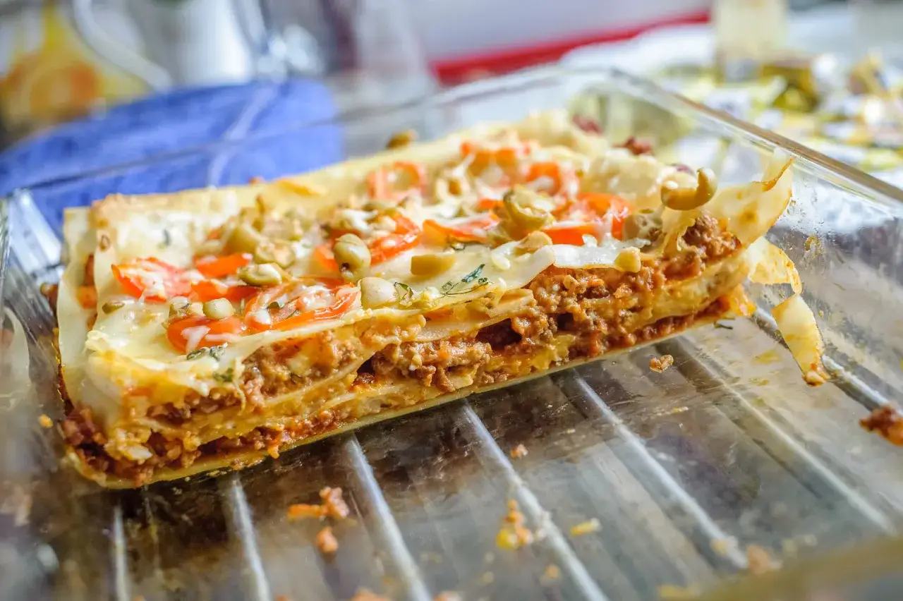 Pyszne, domowe lasagne z mięsem mielonym, pomidorami i oliwkami, gotowe do podania.