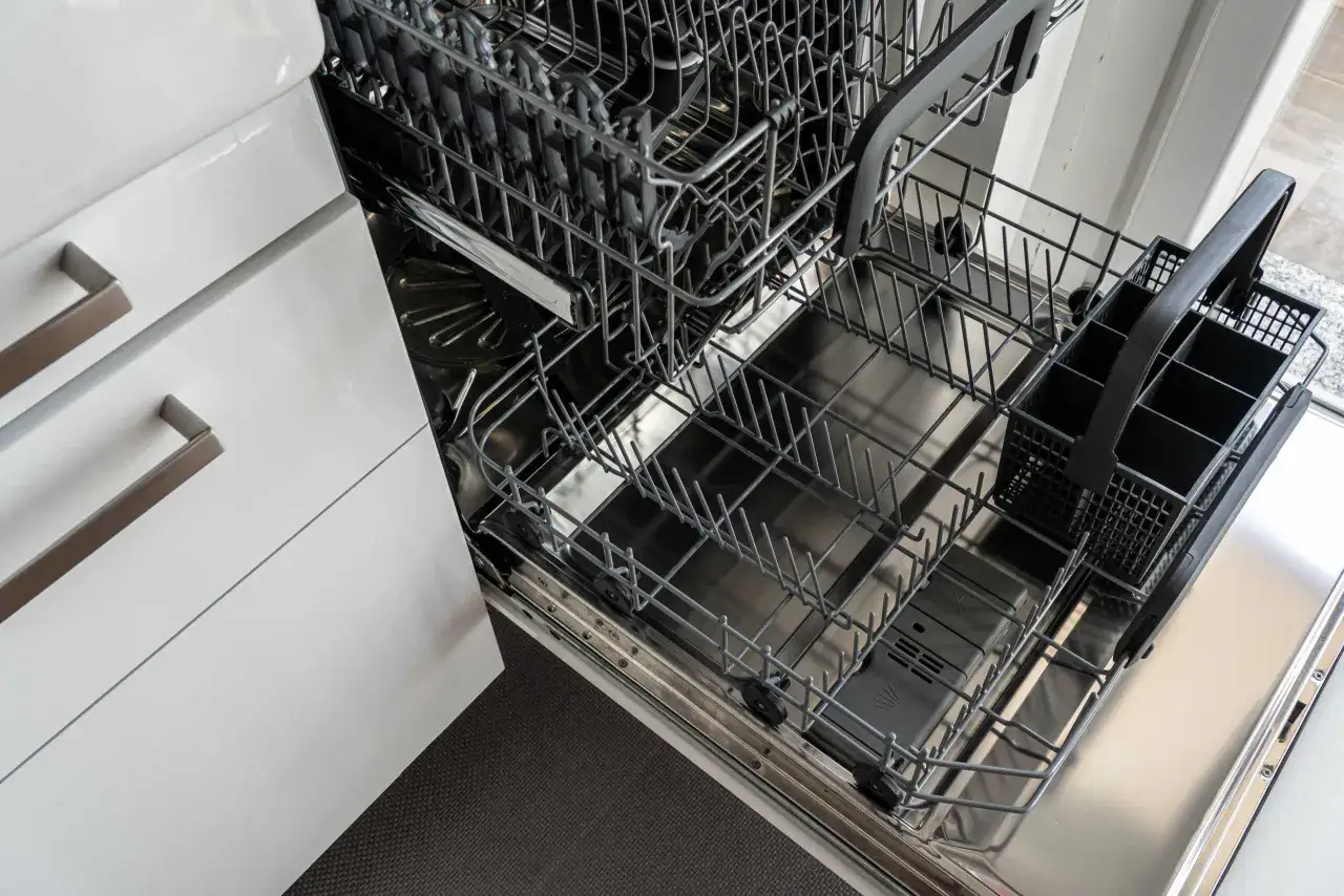 Interno di una lavastoviglie aperta, con cestelli metallici e portaposate. Attenzione: il bicarbonato può rovinare la lavastoviglie.