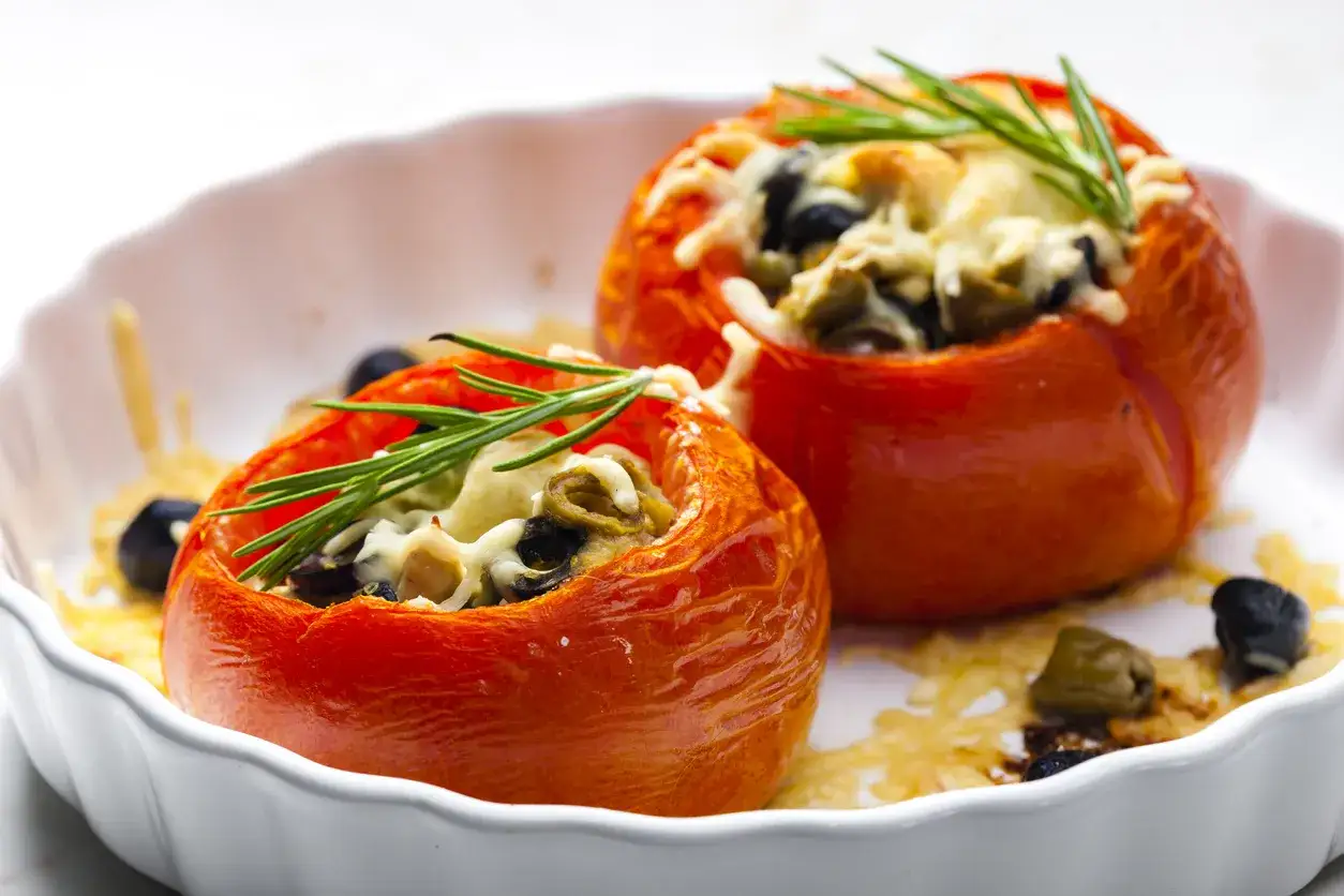 Pomodori ripieni con olive, formaggio fuso e rosmarino. Un'idea gustosa per un antipasto o un secondo piatto.