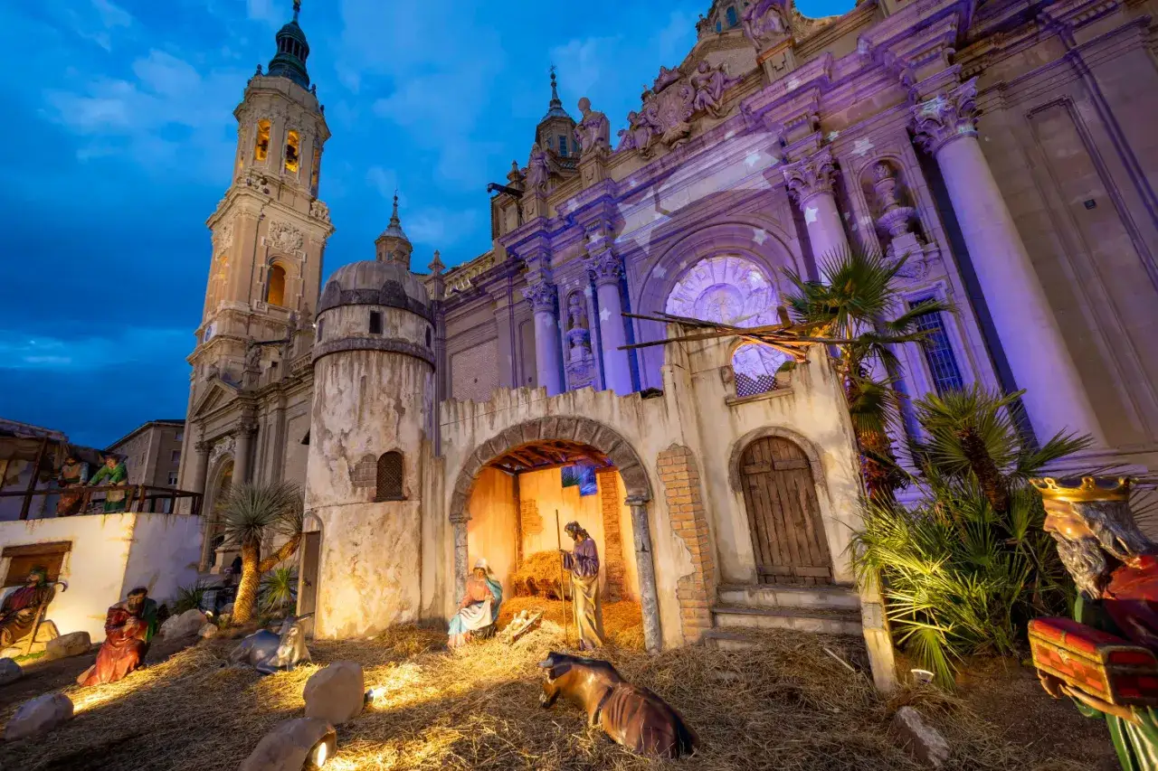 Belén navideño frente a la Basílica del Pilar en Zaragoza. Figuras de la Natividad y Reyes Magos iluminados.