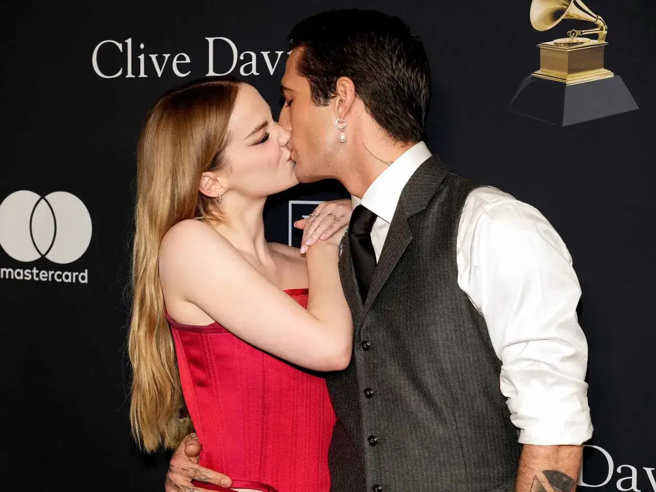 Dove Cameron y su pareja se besan apasionadamente en un evento.