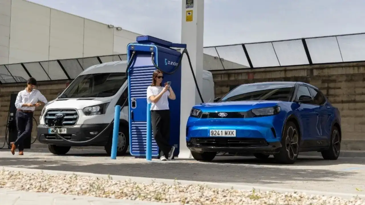 Un hombre y una mujer cargan sus coches eléctricos. La deducción del IRPF por coche eléctrico es una ventaja fiscal.