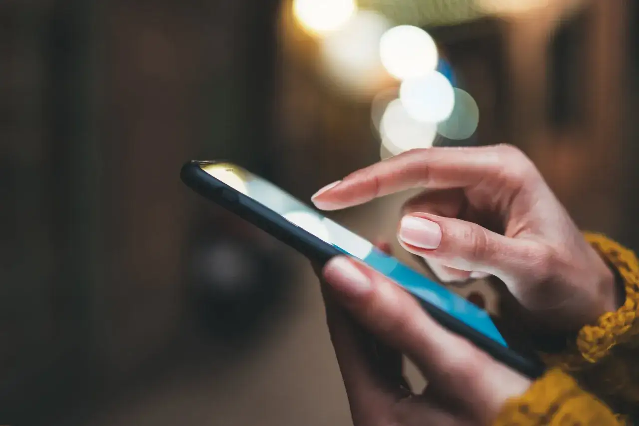 Dita che scorrono su uno smartphone, forse scambiando messaggi o esplorando esempi di sexting.
