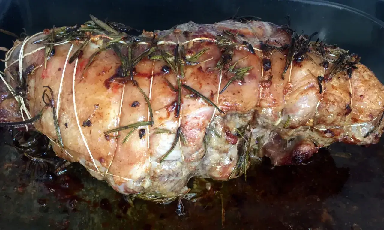 Gigot d'agneau rôti, parfumé au romarin, prêt à être dégusté.