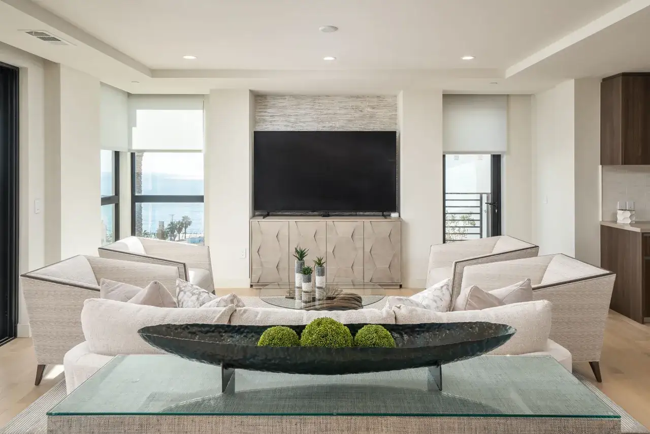 Salon moderne avec une chemin&eacute;e murale TV, des fauteuils confortables et une d&eacute;coration v&eacute;g&eacute;tale.