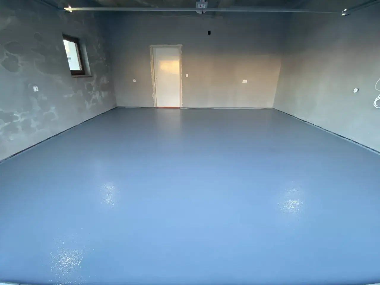 Nowy, gładki, niebieski beton na podłodze garażu. Idealna posadzka do garażu, która jest łatwa w utrzymaniu czystości.