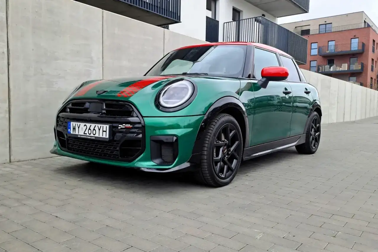 Zielony Mini Cooper z czerwonym dachem i pasami na masce, zaparkowany na kostce brukowej. Zastanawiasz się, ile pali Mini Cooper?