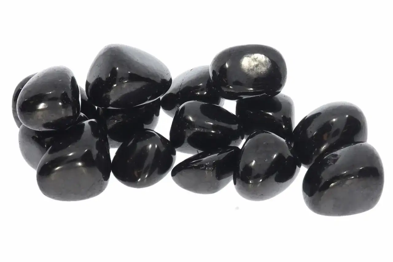 Glänzende, polierte schwarze Steine, die an eine Sammlung von Obsidian erinnern. Ihre dunkle Farbe symbolisiert oft Schutz und Stärke, was die tiefe schwarzer stein bedeutung unterstreicht.