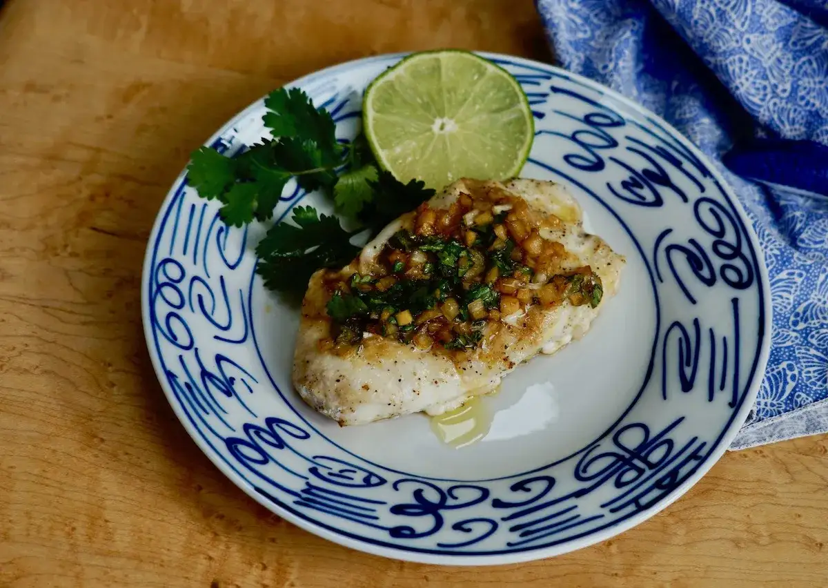 En saftig havsabborre med en smakrik topping av örter och vitlök, perfekt för ett snabbt havsabborre recept. Serveras med lime och koriander.