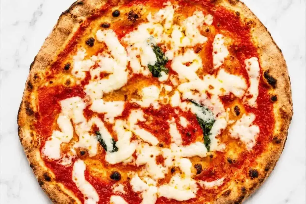 Eine köstliche DOP Pizza Margherita mit geschmolzenem Mozzarella, leuchtend roter Tomatensauce und frischem Basilikum auf einem knusprigen Teig.