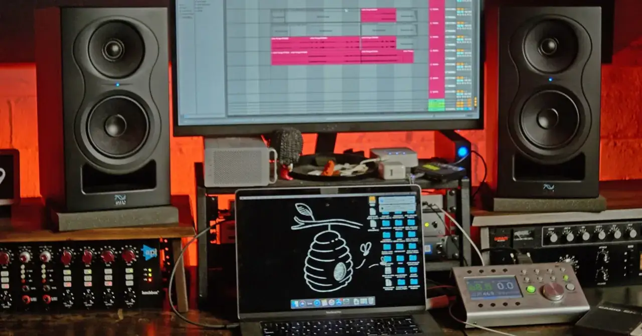 Studio setup z monitorami KRK, laptopem z programem do produkcji muzyki i sprzętem audio. Idealne miejsce do tworzenia dźwięku.