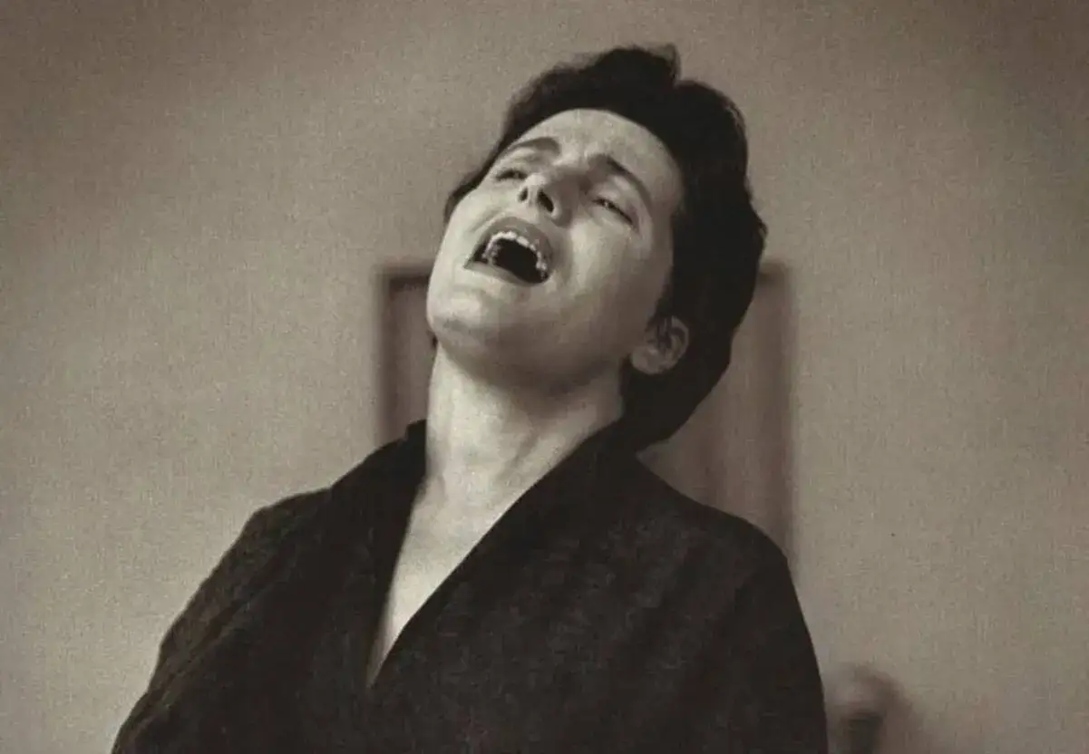 Amalia Rodrigues, królowa fado, w akcie wzruszającego śpiewu. Jej twarz wykrzywiona emocjami, głowa odrzucona do tyłu.