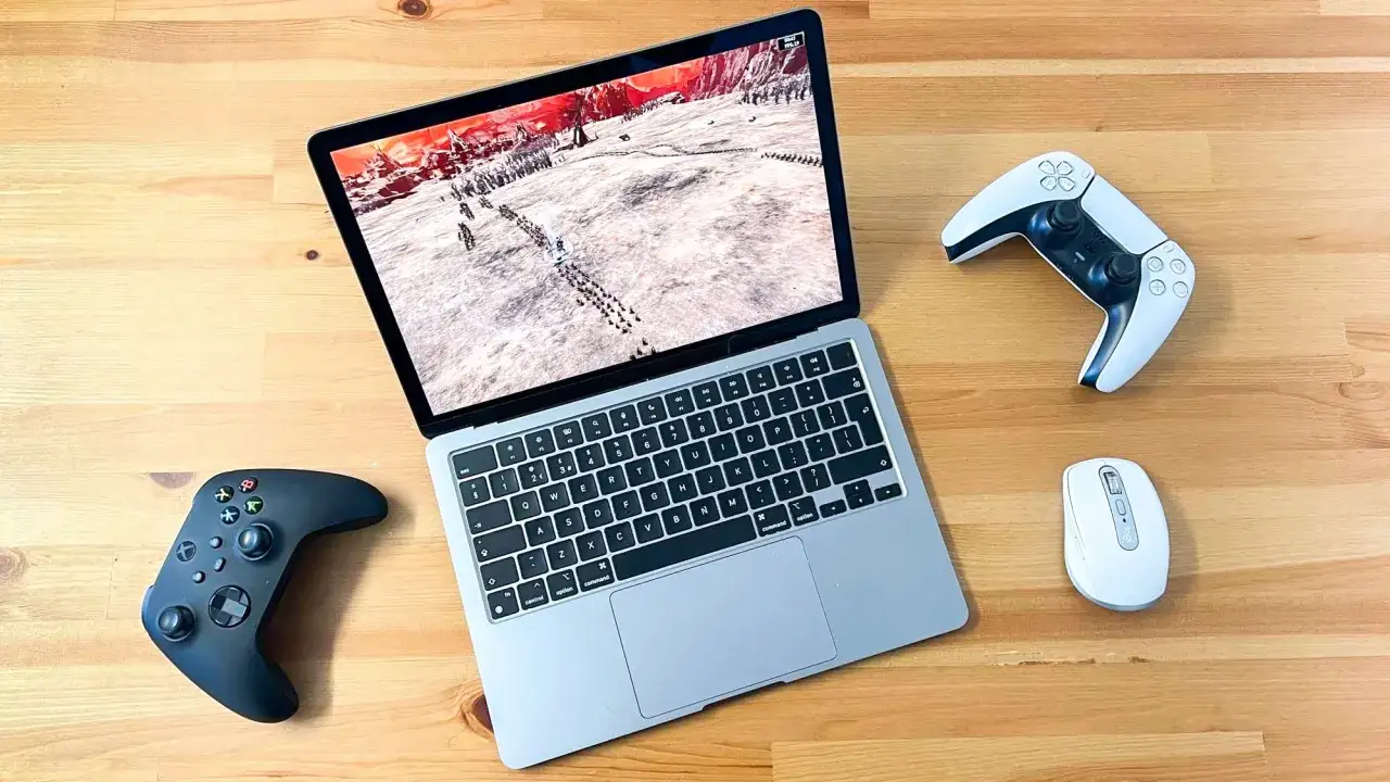 MacBook z grą strategiczną, obok kontrolery do gier i myszka. Idealny zestaw do gier na MacBook.