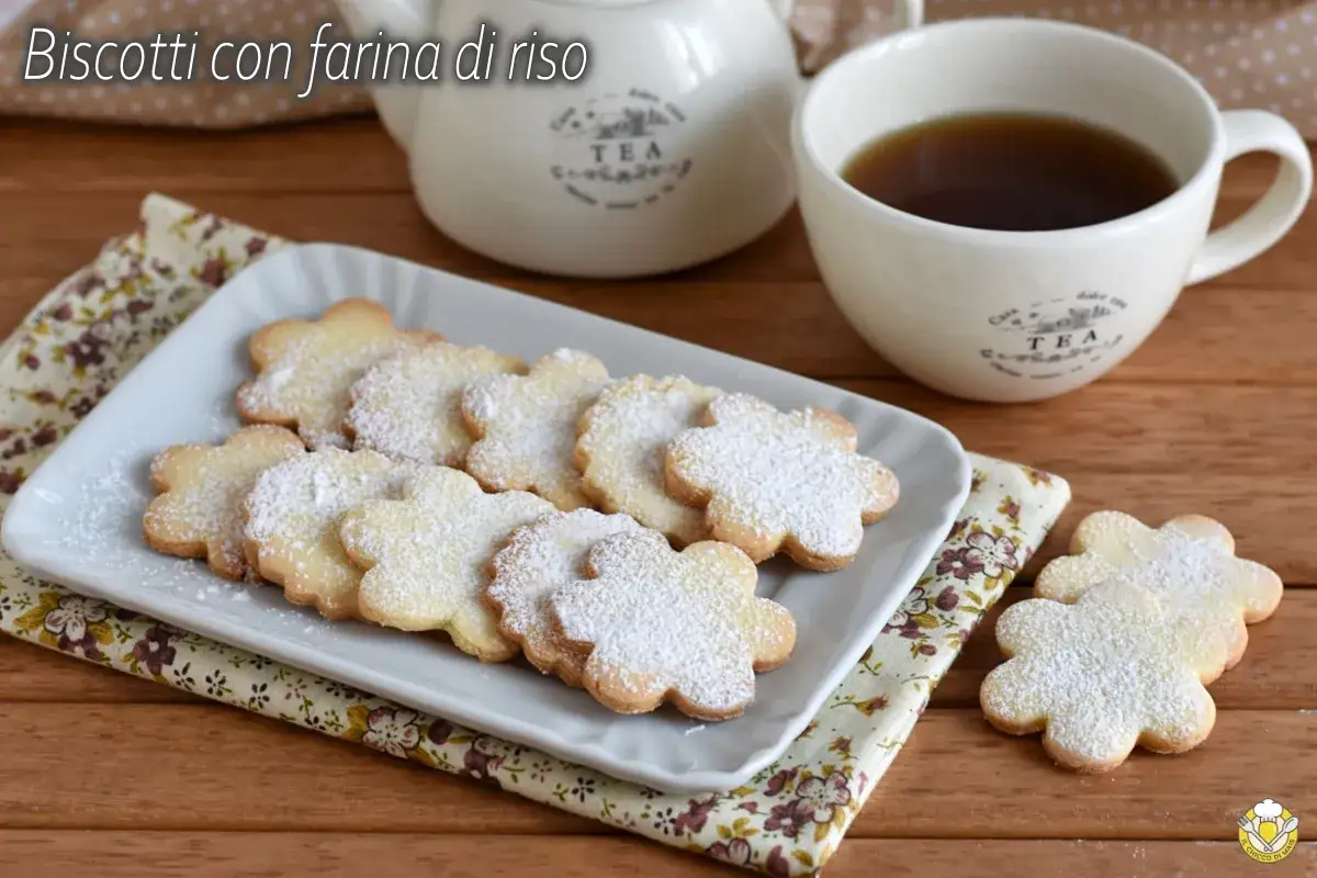 Biscotti con farina di riso a forma di fiore, spolverati di zucchero a velo, serviti con una tazza di t&egrave;.
