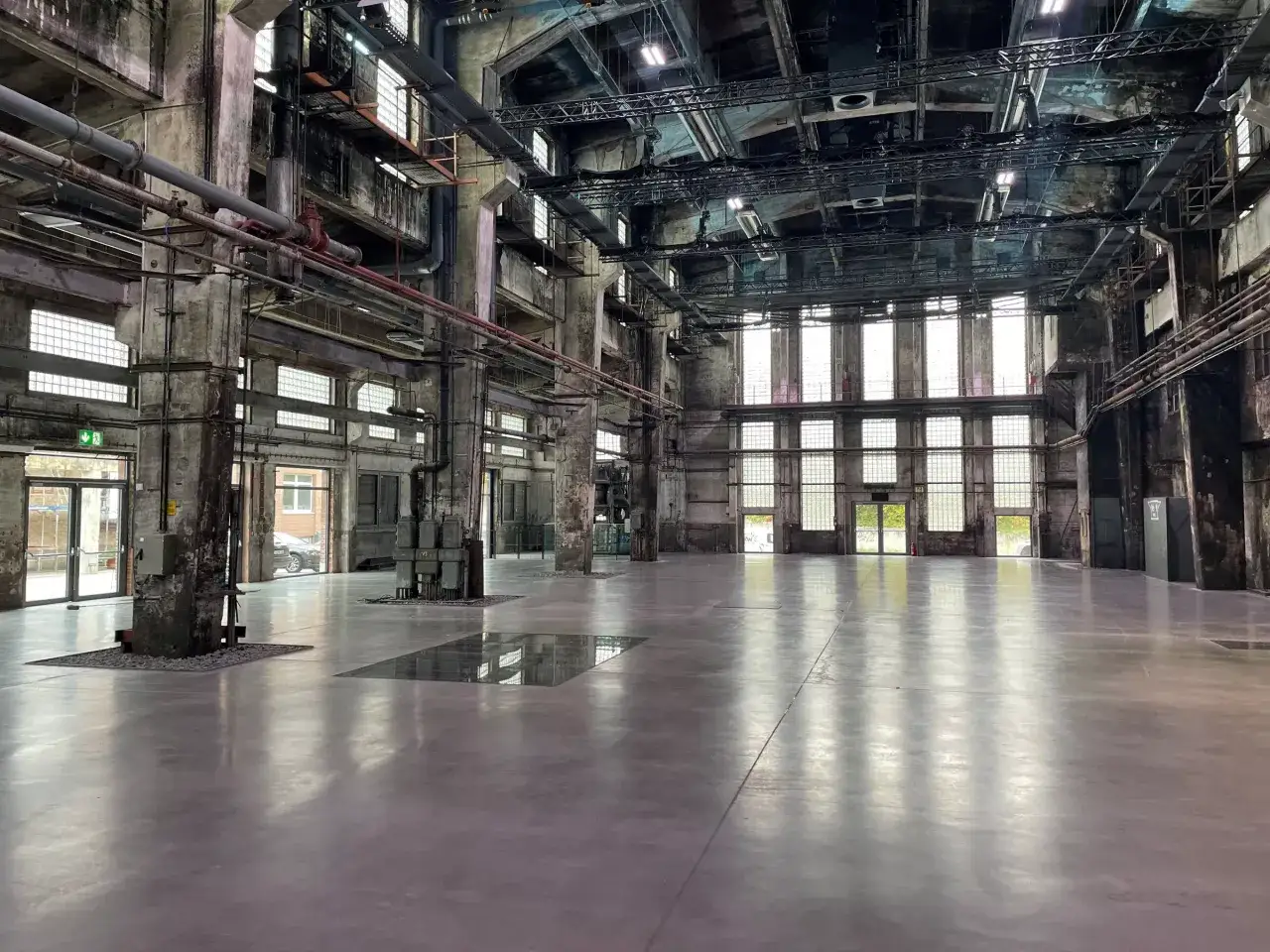 Große, leere Halle mit Betonböden und industrieller Architektur, die an die Motorworld Metzingen erinnert.