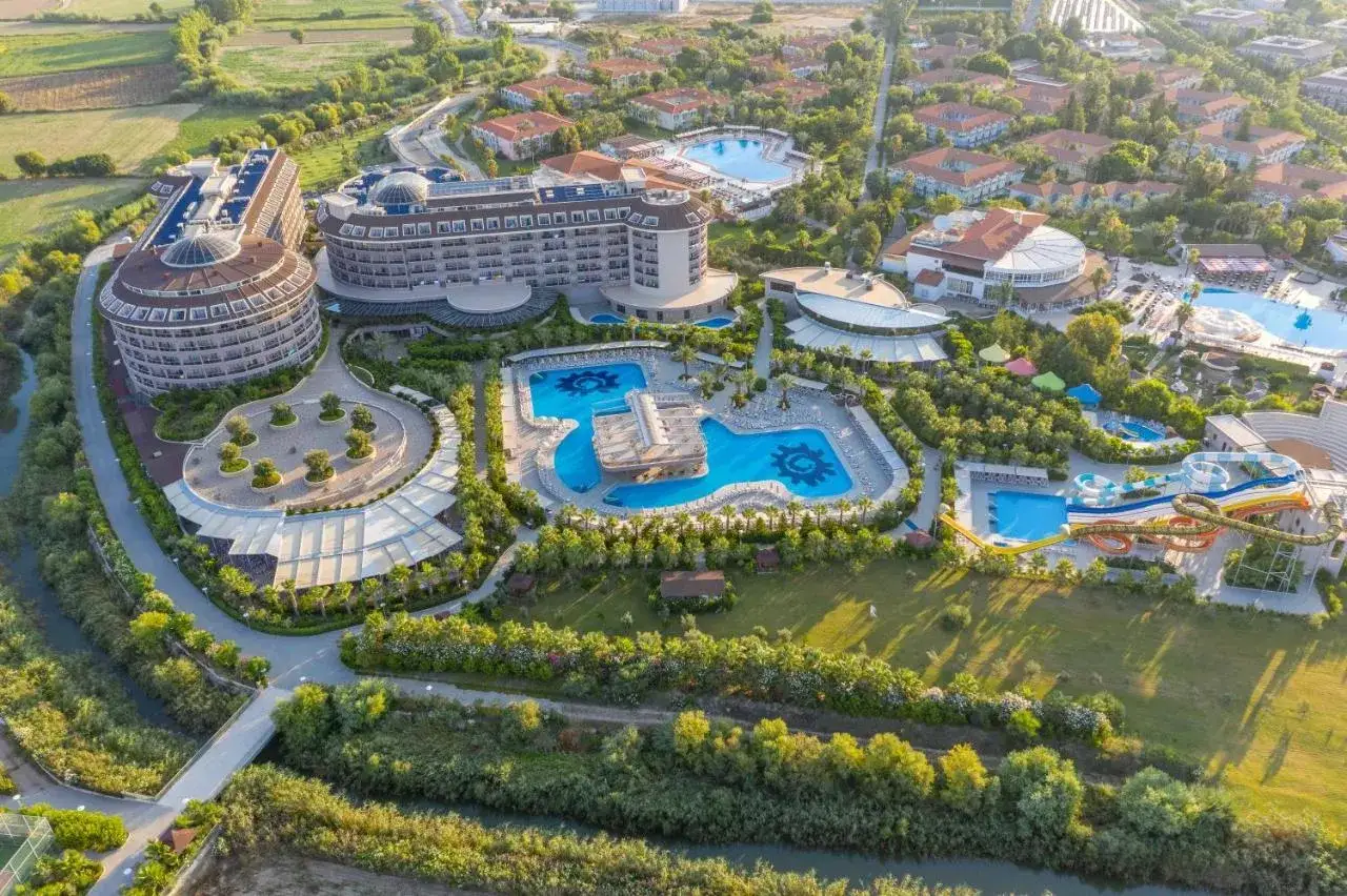 Luksusowy hotel Kizilagac z basenami i zjeżdżalniami wodnymi, otoczony zielenią i rzeką.