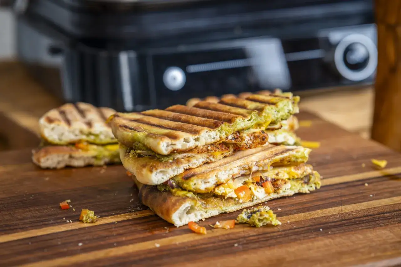 Pyszne panini z kurczakiem, serem i zielonym pesto, świeżo przygotowane na grillu.