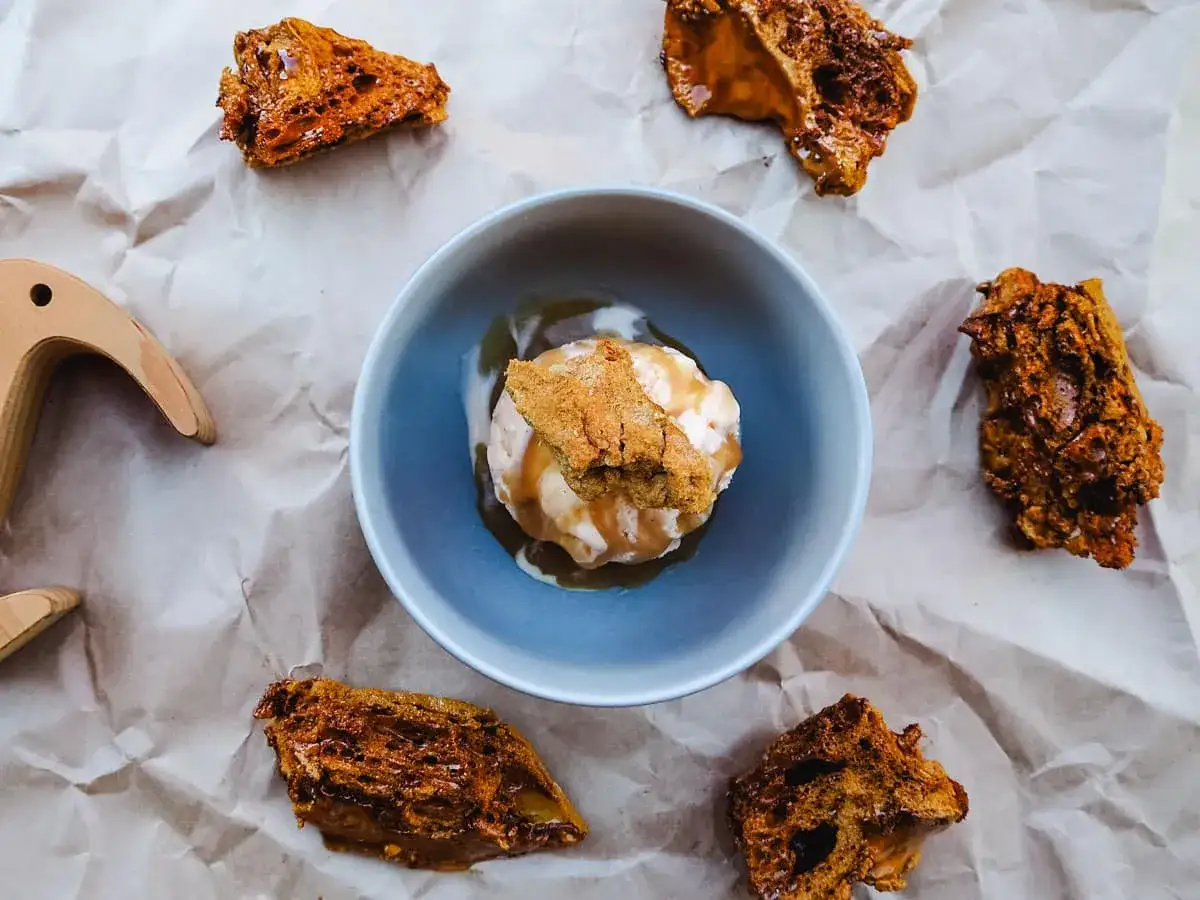 Ein Sch&uuml;sselchen mit cremigem Eis, garniert mit Keks und Karamell. Umgeben von knusprigen St&uuml;cken, die an ein Hokey Pokey Eis Rezept erinnern.