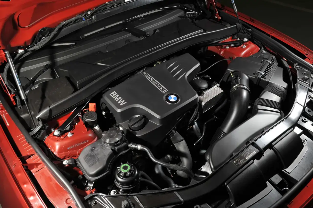 Silnik BMW Twin Power Turbo, model n20, w czerwonym aucie. Widoczne elementy układu dolotowego i chłodzenia.