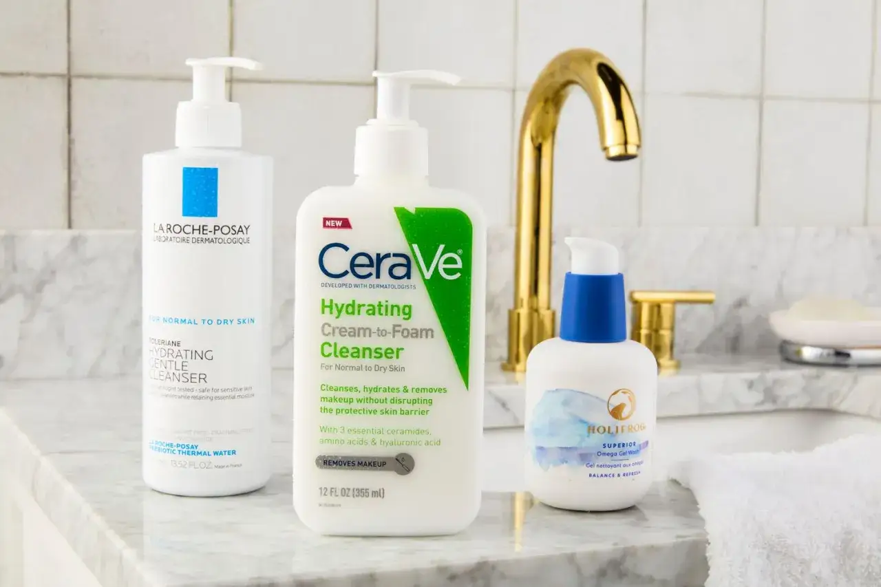 Trois nettoyants pour le visage : La Roche-Posay, CeraVe et Holifrog, sur un lavabo. Idéal pour savoir comment nettoyer son visage.
