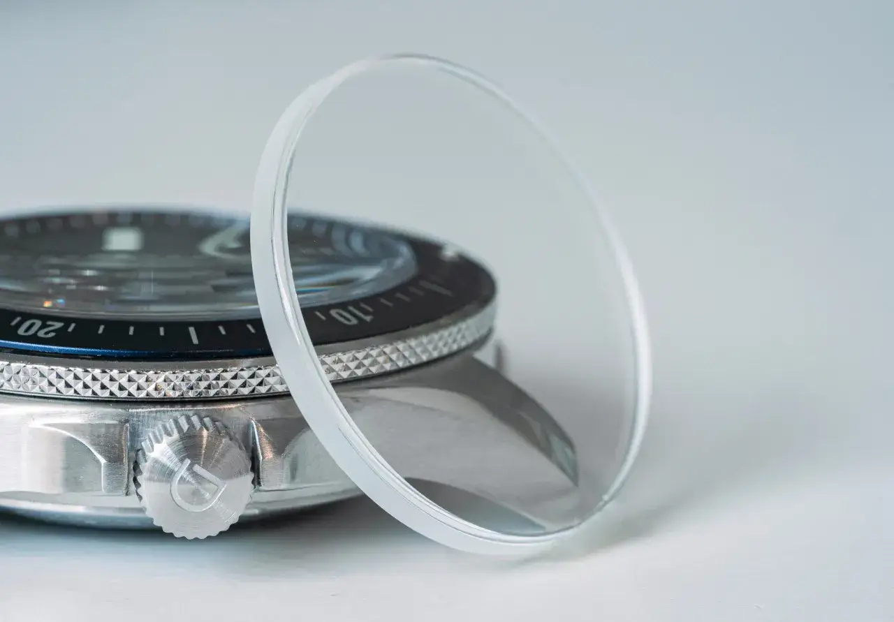 Un cristal hesalite transparente, listo para proteger la esfera de un reloj de buceo con su diseño clásico y duradero.