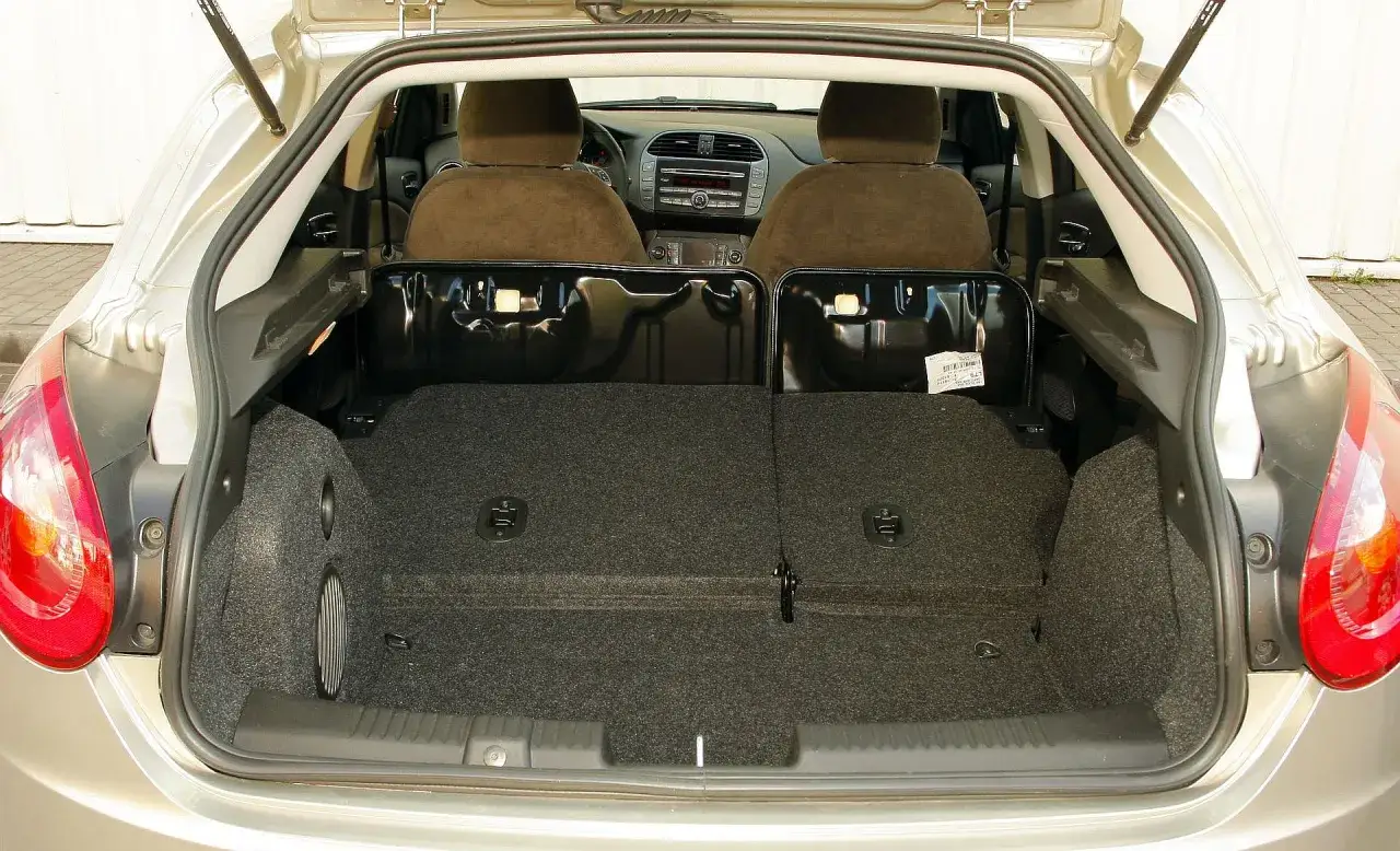 Wnętrze samochodu z otwartym bagażnikiem. Widoczne fotele, deska rozdzielcza i wyłożony wykładziną bagażnik. Bravo!