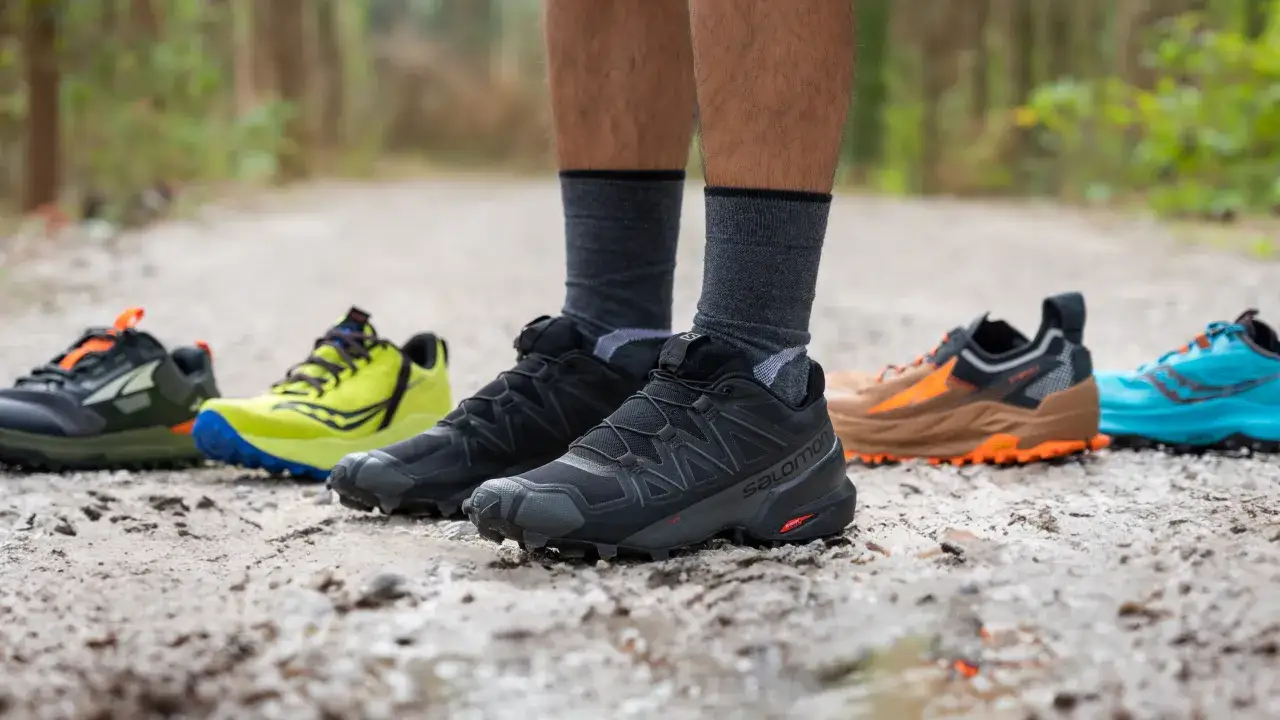 Buty trailowe co to? Różne modele butów do biegania w terenie, od czarnych Salomon po jaskrawożółte i niebieskie.